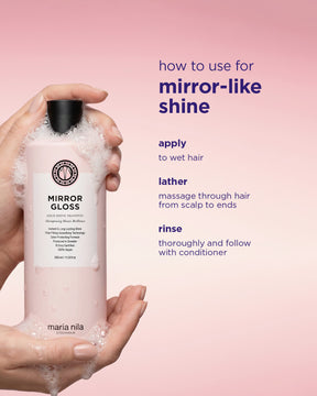Hand holding a bottle of Maria Nila Mirror Gloss Shampoo with usage instructions on a pink background